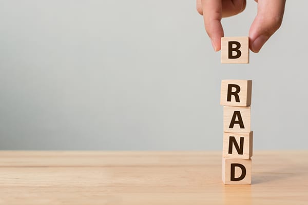 person stacking blocks that spell Brand