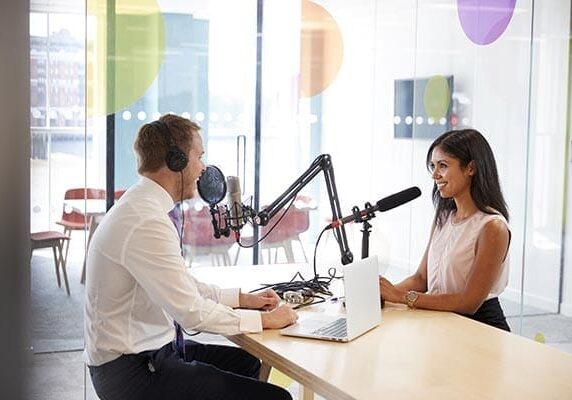 coach and interviewee recording a podcast in an office
