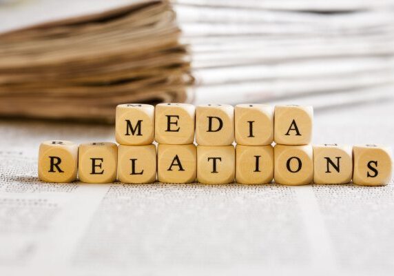 small blocks in front of a stack of news paper spelling Media Relations